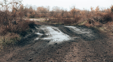 Obraz na płótnie Canvas Dark rural dirt road with mud. Gravel road landscape empty countryside.