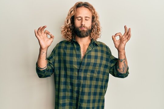 Handsome man with beard and long hair wearing casual clothes relax and smiling with eyes closed doing meditation gesture with fingers. yoga concept.