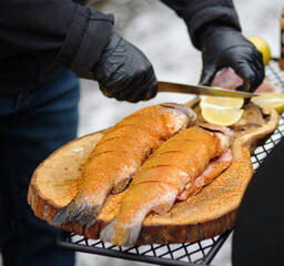 Grillman prepares trout for grilling, cuts lemon.