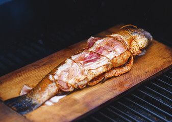 Trout on a cedar plank with lemon and bacon grilled. Selective Focus.