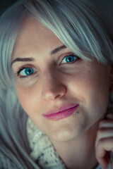close up indoor portrait of an attractive young woman with blue eyes and platinum-blond hair, on a   grey  background