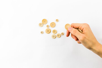 hand throwing a handful of wooden buttons as if it were currency cash on white background