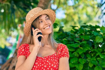 Young blonde tourist woman wearing summer style talking on the smartphone at the park