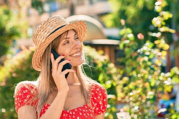 Young blonde tourist woman wearing summer style talking on the smartphone at the park
