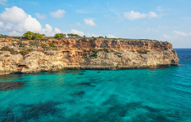 Clear blue green sea water, rocky cliffs around - nice sunny day at Ansa de s'Estri, Mallorca