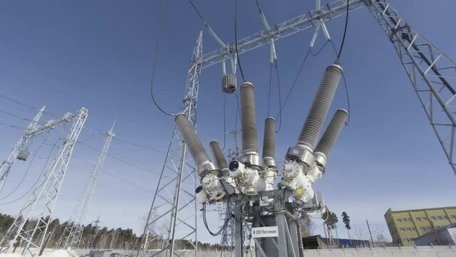 Bottom view of electricity grid and transformer on blue cloudy sky background. Action. Power line at the electricity generating plant.