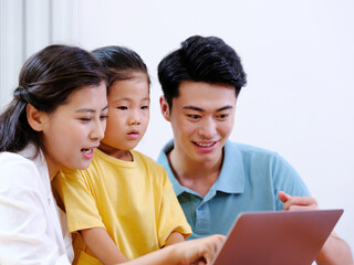 Obraz premium Happy family of three using laptop