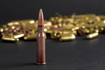 Copper machine gun bullet, more blurred yellow ammo on black board background