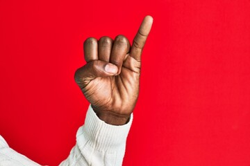 Arm and hand of african american black young man over red isolated background showing little finger...