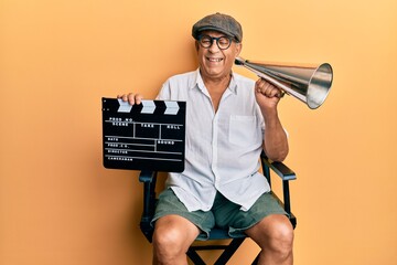 Handsome mature director man holding video film clapboard and louder winking looking at the camera...