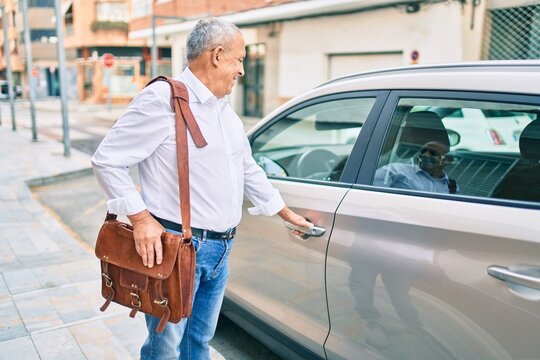 Senior man smiling happy opening car at the city.