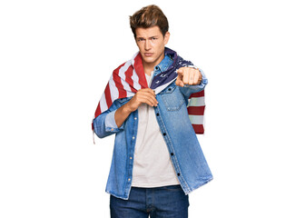 Handsome caucasian man holding united states flag pointing with finger to the camera and to you, confident gesture looking serious