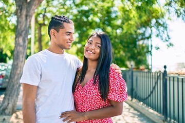 Naklejka premium Young latin couple smiling happy and hugging at the park.