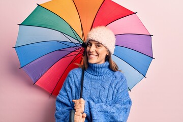 Young beautiful woman holding colorful umbrella looking positive and happy standing and smiling with a confident smile showing teeth