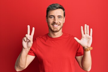 Fototapeta premium Handsome caucasian man wearing casual red tshirt showing and pointing up with fingers number seven while smiling confident and happy.