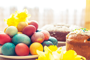Easter orthodox sweet bread, kulich, colored eggs and a bouquet of daffodils.