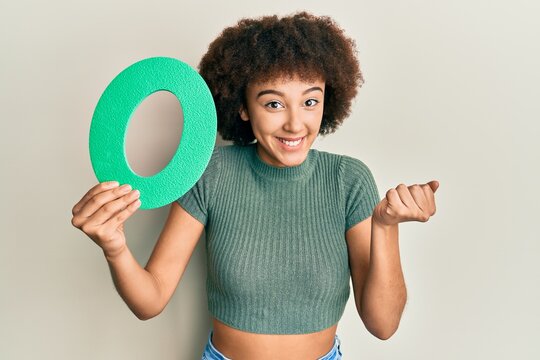 Young hispanic girl holding number zero screaming proud, celebrating victory and success very excited with raised arm