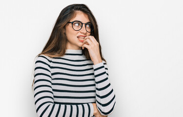 Young beautiful teen girl wearing casual clothes and glasses looking stressed and nervous with hands on mouth biting nails. anxiety problem.