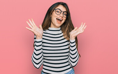 Young beautiful teen girl wearing casual clothes and glasses celebrating crazy and amazed for...