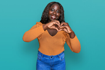 Young african woman wearing casual clothes smiling in love doing heart symbol shape with hands. romantic concept.