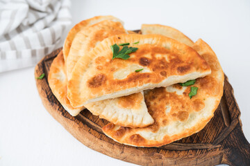 Homemade fried empanadas with pork, chebureks with mushrooms on a wooden board