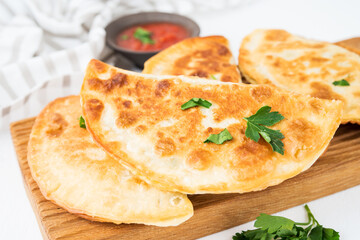 Homemade fried empanadas with pork, chebureks with mushrooms on a wooden board