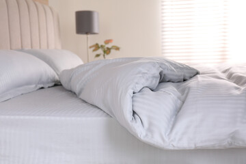 Fototapeta na wymiar Comfortable bed with soft blanket indoors, closeup