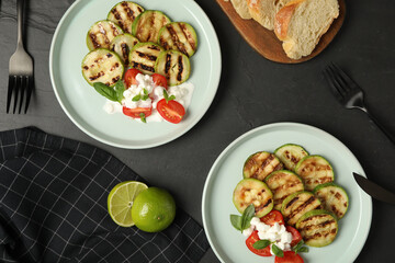 Flat lay composition with delicious grilled zucchini slices on black table