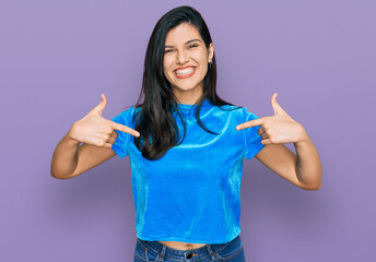 Young hispanic woman wearing casual clothes looking confident with smile on face, pointing oneself with fingers proud and happy.