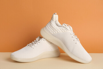 Pair of stylish sport shoes on orange background