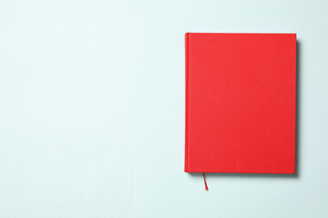 Book with red cover on light blue background, top view. Space for text
