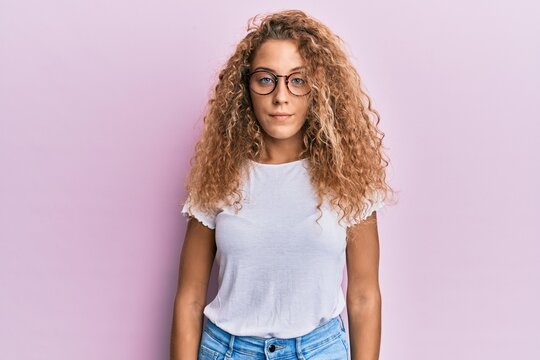 Beautiful caucasian teenager girl wearing white t-shirt over pink background relaxed with serious expression on face. simple and natural looking at the camera.