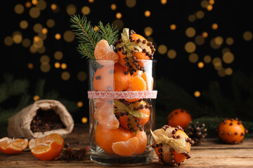Fototapeta na wymiar Christmas composition with tangerine pomander balls in glass against blurred lights
