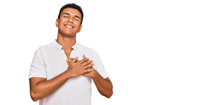 Young arab man wearing casual clothes smiling with hands on chest with closed eyes and grateful gesture on face. health concept.