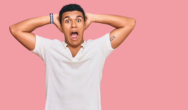Young arab man wearing casual clothes crazy and scared with hands on head, afraid and surprised of shock with open mouth