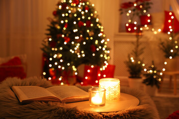 Book and candles in room with Christmas decorations. Interior design
