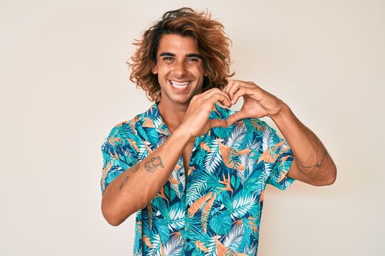 Young hispanic man wearing summer shirt smiling in love showing heart symbol and shape with hands. romantic concept.