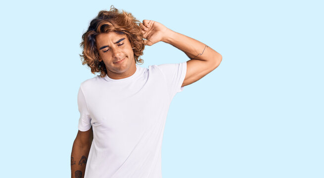 Young hispanic man wearing casual white tshirt stretching back, tired and relaxed, sleepy and yawning for early morning