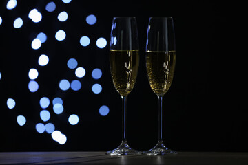 Glasses of champagne on grey table against blurred lights. Space for text