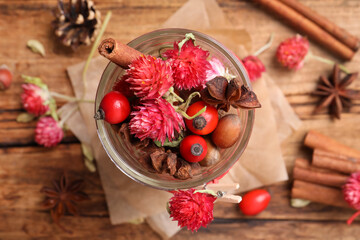 Aromatic potpourri in glass jar on wooden background, flat lay
