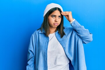 Young latin woman wearing cute wool cap worried and stressed about a problem with hand on forehead, nervous and anxious for crisis