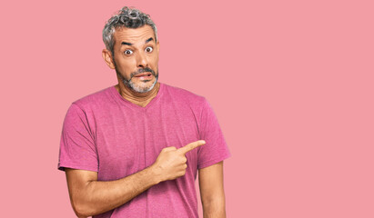 Middle age grey-haired man wearing casual clothes pointing aside worried and nervous with...