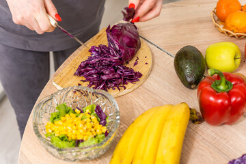 Beautiful young woman is preparing vegetable salad in the kitchen. Cooking At Home