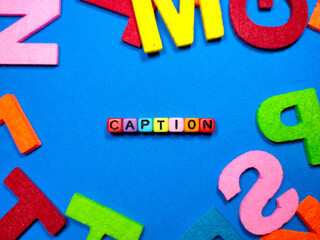 Selective focus.Colorful dice with word CAPTION on blue background.Shot were noise and film grain.