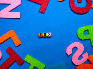 Selective focus.Colorful dice with word SEX on blue background.Shot were noise and film grain.