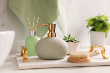 Tray with toiletries, air reed freshener and plant on countertop in bathroom
