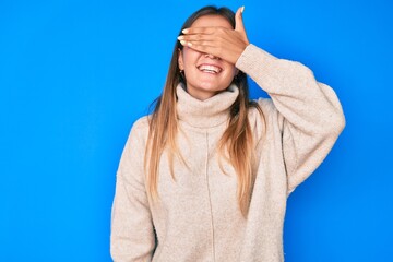 Naklejka premium Beautiful caucasian woman wearing wool winter sweater smiling and laughing with hand on face covering eyes for surprise. blind concept.
