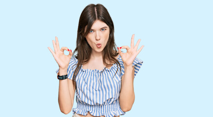 Young beautiful caucasian girl wearing casual clothes looking surprised and shocked doing ok approval symbol with fingers. crazy expression