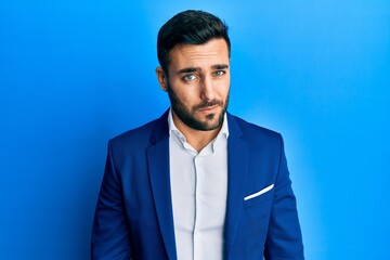 Young hispanic businessman wearing business jacket skeptic and nervous, frowning upset because of...