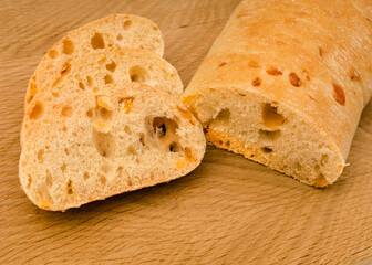 Ciabatta - Italian bread with cheese cut into slices on a wooden board